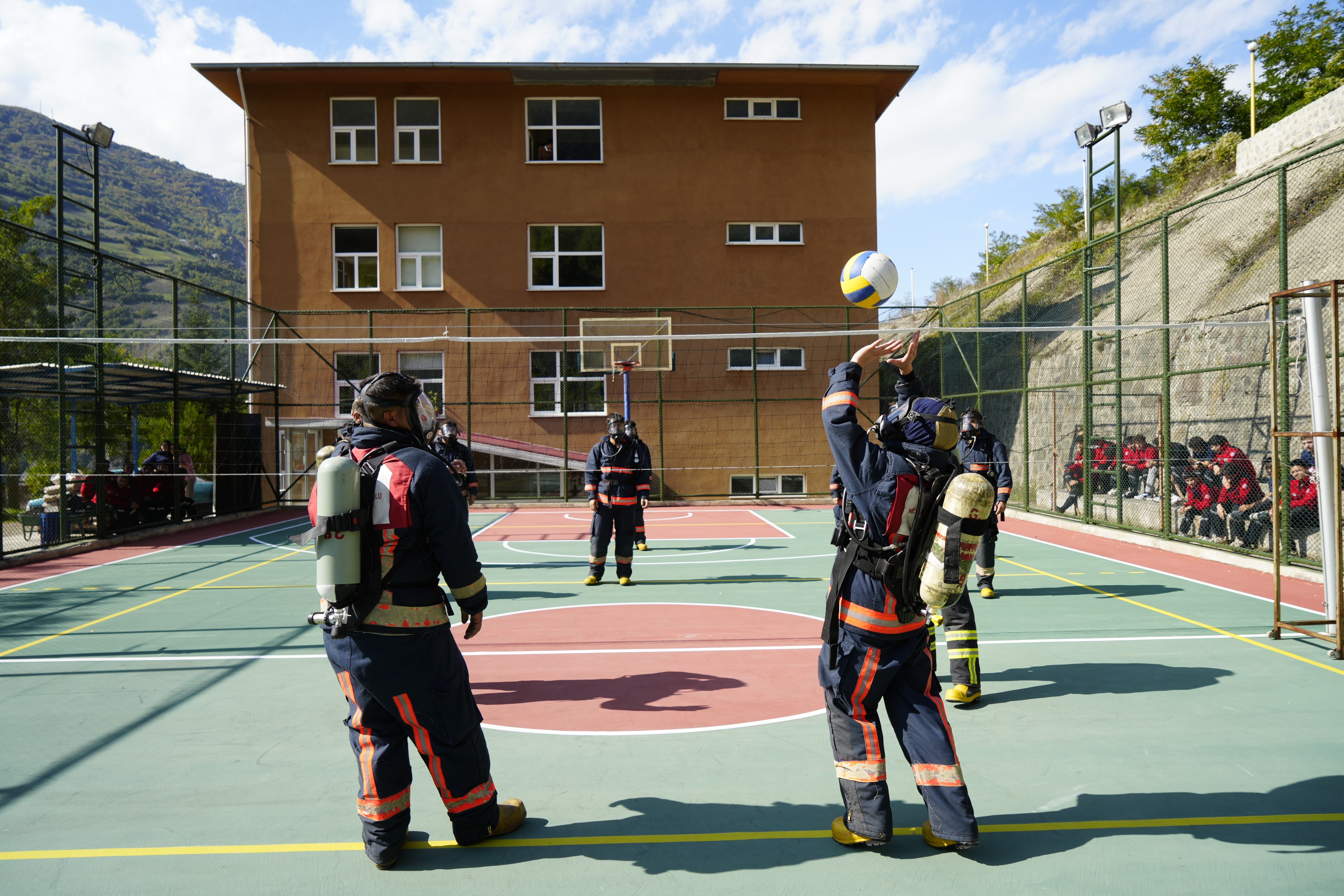 “Oksijen bittiğinde maç biter”
Temel amaçlarının öğrencilerin nefes kontrolünü ve eforlu çalışmalardaki hava tüketimini deneyimlemesi olduğunu belirten Öğr. Gör. Erdem Soylu, uygulamayı şu sözlerle anlattı:
“Yangına müdahale sırasında kullanılan ekipmanları öğrencilerimize tanıtmakla kalmıyor, onları sahadaki zorluklara da hazırlıyoruz. Tüplerin kaç dakikada tükendiğini birebir yaşayarak öğreniyorlar. Voleybol oyunu sayesinde hem eğleniyorlar hem de oksijenlerini kontrollü kullanmayı öğreniyorlar. Oyunun kuralı basit: Oksijen biterse, oyun biter.”